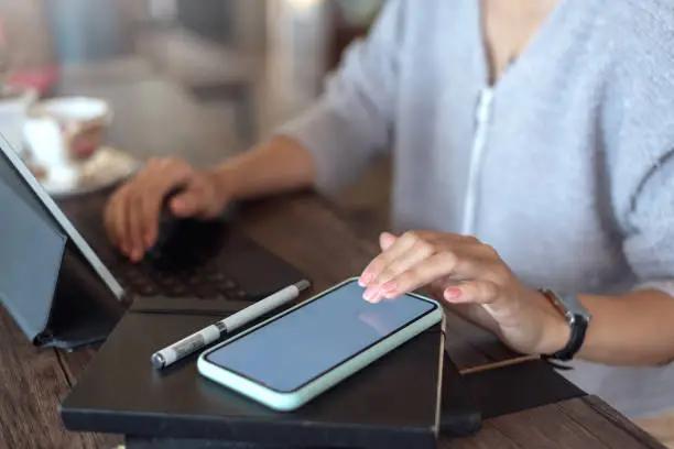 A person using a smartphone on a table with a tablet and other devices