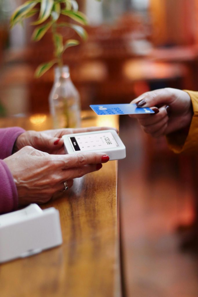 A person holding a small card reader as another taps a card