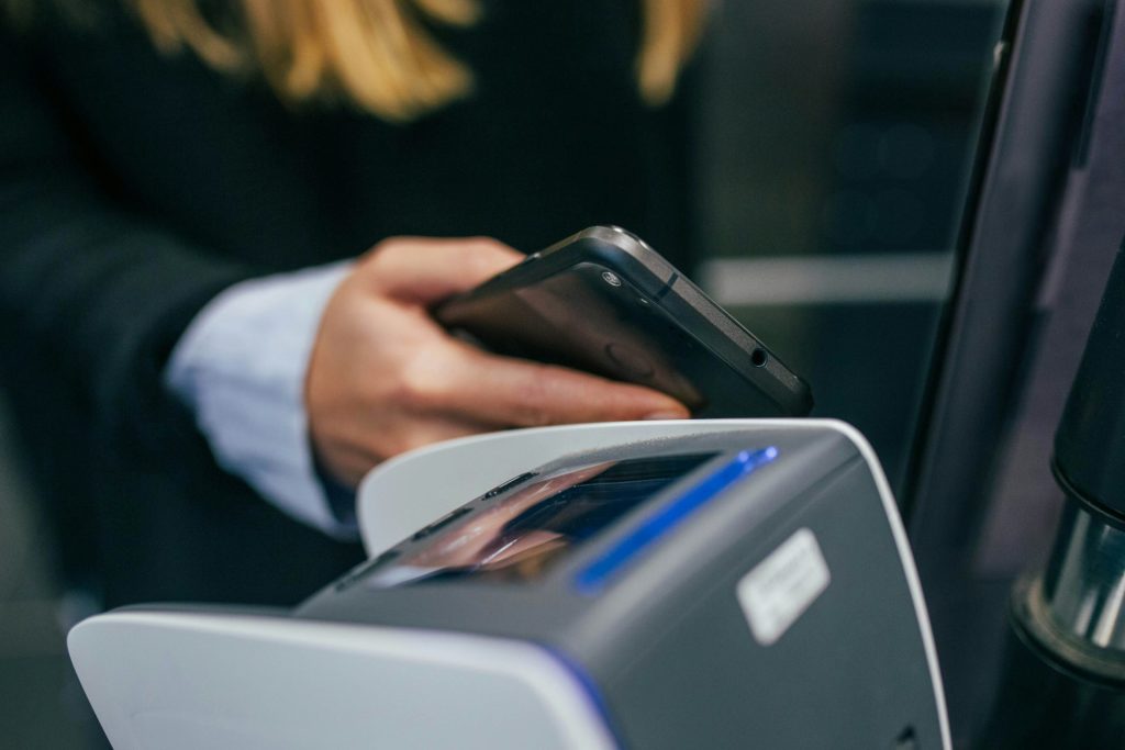 A close-up of someone making a payment using a smartphone on a payment terminal